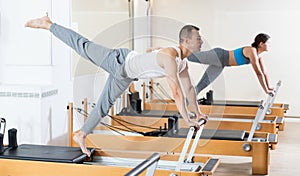 Focused man practicing exercises on Pilates reformer in studio photo