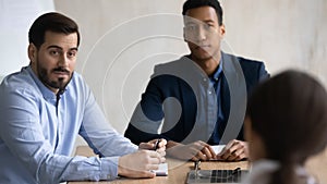 Focused young mixed race teammates listening to colleague in office.