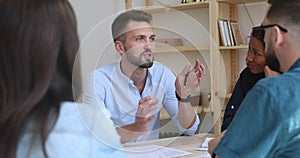 Focused young multiracial colleagues listening to confident team leader.