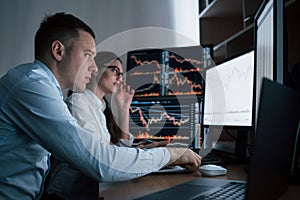 Focused young people. Team of stockbrokers are having a conversation in a office with multiple display screens