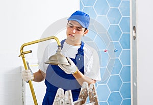 Focused young plumber installing shower in apartment under renovation