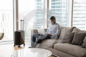 Focused young professional man working on laptop on business trip