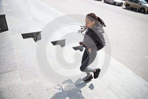 Focused young runner with cornrows jogging upstairs