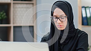 Focused young Saudi business woman working remotely distance e learning use laptop medium closeup