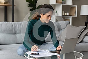 Focused young woman managing household budget indoors.