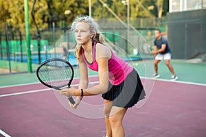 Focused young woman playing tennis on court, preparing to hit to return ball. Concept of sport training
