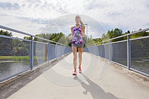 Focused young woman running on bridge over a lake