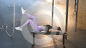 Focused young woman training legs on the bench in the gym.