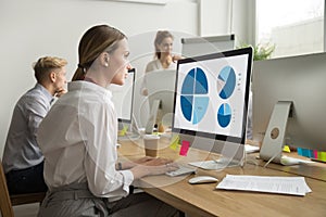 Focused woman working with statistics charts using computer in o