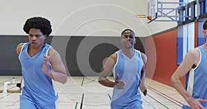 Focussed diverse male basketball team training, sprinting on indoor court, slow motion