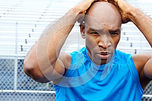 Focussing his thoughts before the race. Close up portrait of a male athlete touching his head in concentration.