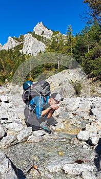 Foelzkogel - Thirsty hiker man drinking fresh cold water from alpine river with panoramic view of majestic Hochschwab massif