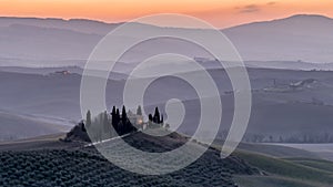 The fog covers the hills of the Val d`Orcia at the first light of dawn, Siena, Tuscany, Italy