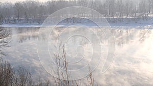 Fog creeps over the river against the background of the rising sun. Fog forms in the areas, which then merges with the