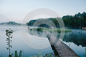 Fog, grass, trees against the backdrop of lakes and nature. Fishing background. Misty morning. nature. Wild areas. bridge over the