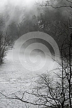 Fog hovers on top of a river bed in winter season.