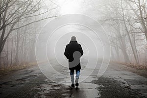 Fog landscape. Man walking  alone on scary foggy misty road