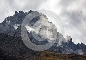 Fog, low clouds and gusty wind in the mountains with rocky terrain