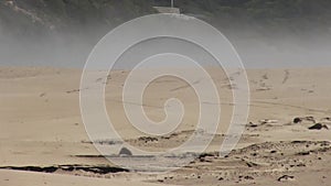 Fog Moving Across Sand Beach With Cliff In Background