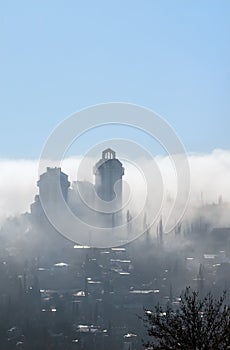 Fog over the city. City is covered with mist in sunlight and blu