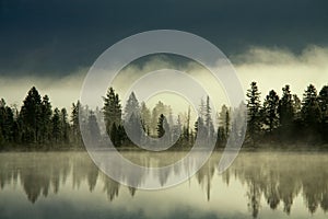 Fog over the forest by the shore of the lake.