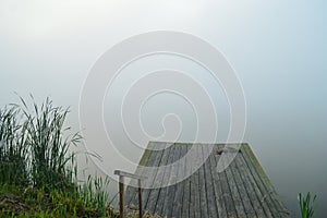 Fog over the water in the morning with place for fishing, pier. mist over the lake in the early morning.