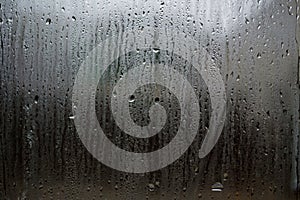 Fog and raindrops on window glass, dark background and lantern l