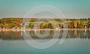 Fog rises over the lake at sunrise on a chilly morning as fall foliage peaks through the mist