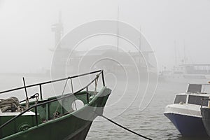 Fog in the seaport. Old green fishing baot.