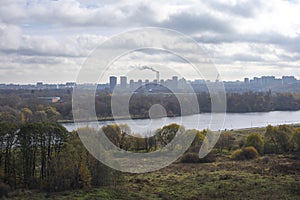 Foggy autumn landscape Moscow Kolomenskoye park. A skyscraper and a smoking chimney and an idyllic landscape with a river in the