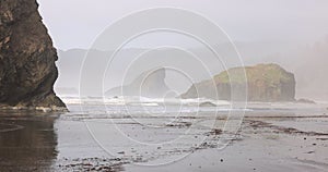 A foggy beach with rocks and a rocky shoreline