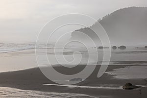 A foggy beach with a rocky shoreline