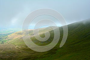 Foggy clouds coming from green hills near Pen y Fan peak, Brecon Beacons National Park, Wales, UK