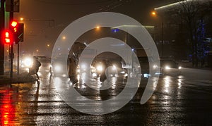 Foggy night crossing with pedestrains, wet asphalt road, street and car lights photo