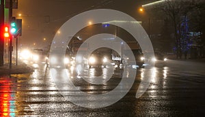 Foggy night crossing with pedestrains, wet asphalt road, street and car lights photo