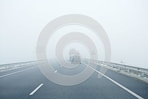 Foggy gray road, cars driving into the fog