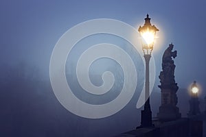 Foggy image of Prague Charles bridge and street lantern at night