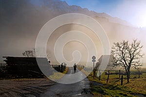 Countryside misty landscape with person silhouette walking alone on the foggy walkway