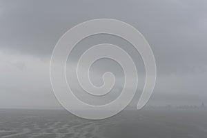 Foggy, misty and cloudy grey seascape with horizon at the sea or ocean