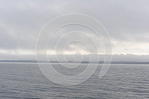 Foggy, misty and cloudy grey seascape with horizon at the sea or ocean