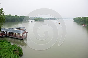 Foggy misty natural chinese landscape. Park with lake and boats near Summer Palace, Beijing