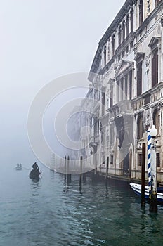 Foggy (misty) Venice. Canal, historical, houses and gondoliers with gondolas on thick fog.