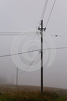 A foggy morning in the countryside in Finland, old electric and telephone wires running through the air