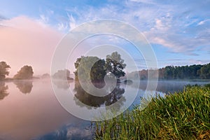 Foggy morning. Dawn outside the city. It will be a warm day. Morning fog on the lake