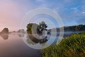 Foggy morning. Dawn outside the city. It will be a warm day. Morning fog on the lake