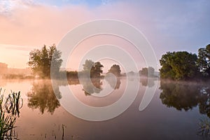 Foggy morning. Dawn outside the city. It will be a warm day. Morning fog on the lake