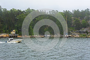 Foggy morning at Helsinki archipelago. Mist landscape with fast motorboat