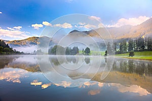 Foggy morning landscape in Alps mountain and lake with reflections
