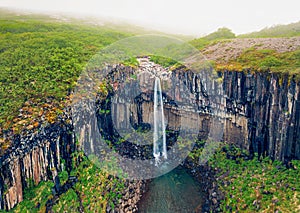 Foggy morning view from flying drone of famous Svartifoss Black Fall Waterfall.