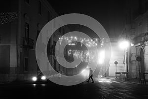 Foggy night scene with solitary man and christmas light decorations